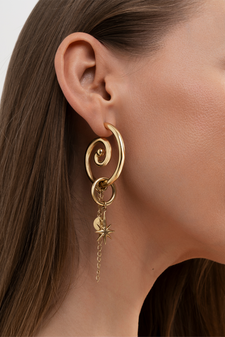 Gold spiral earring with star detail worn by a model